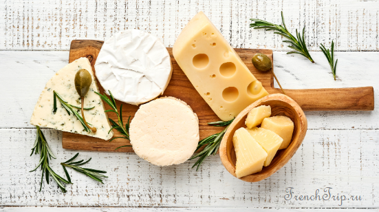 A cheese board with several French cheeses and rosemary