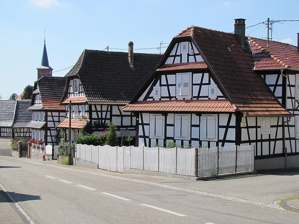 A white half-timbered farmhouse with a fenced garden in Hunspach