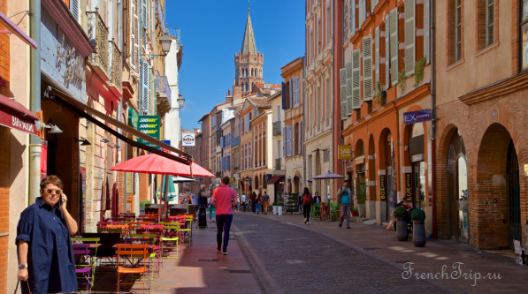 A street of pink brick houses in Toulouse with the bell tower of Saint-Sernin behind