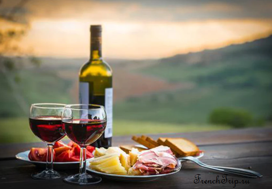 Two glasses of red wine and a bottle on a table outdoors