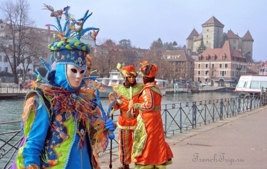 Masked figures posing for photographers in Annecy old town